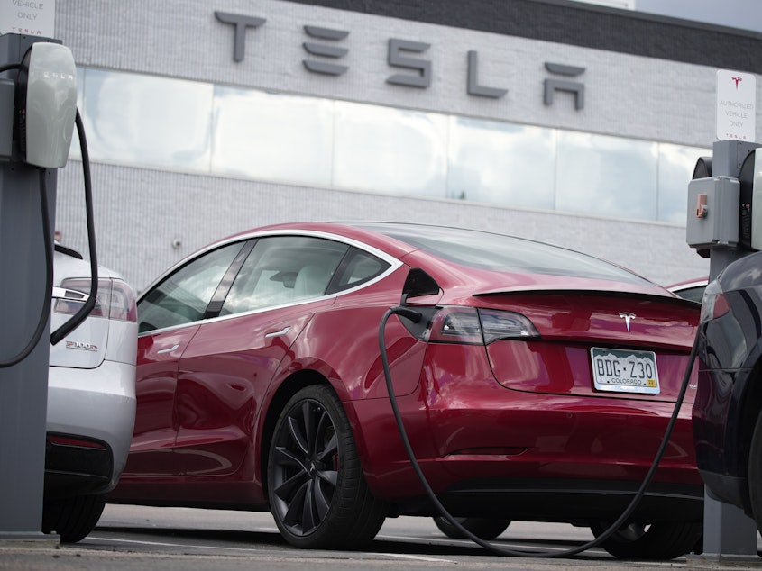 caption: A 2021 Model 3 sedan sits in a lot at a Tesla dealership in Littleton, Colo., on June 27, 2021. Tesla is recalling nearly 54,000 vehicles because their "Full Self-Driving" software lets them roll through stop signs without coming to a complete halt.