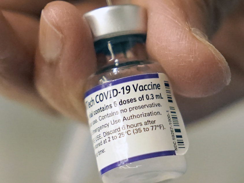 caption: A doctor loads a dose of Pfizer COVID-19 vaccine into a syringe, on Dec. 2, 2021, at a mobile vaccination clinic in Worcester, Mass.