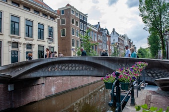 caption: The almost 40-foot 3D-printed pedestrian bridge designed by Joris Laarman and built by Dutch robotics company MX3D has been opened in Amsterdam six years after the project was launched. The bridge, which was fabricated from stainless steel rods by six-axis robotic arms equipped with welding gear, spans the Oudezijds Achterburgwal in Amsterdam's Red Light District.