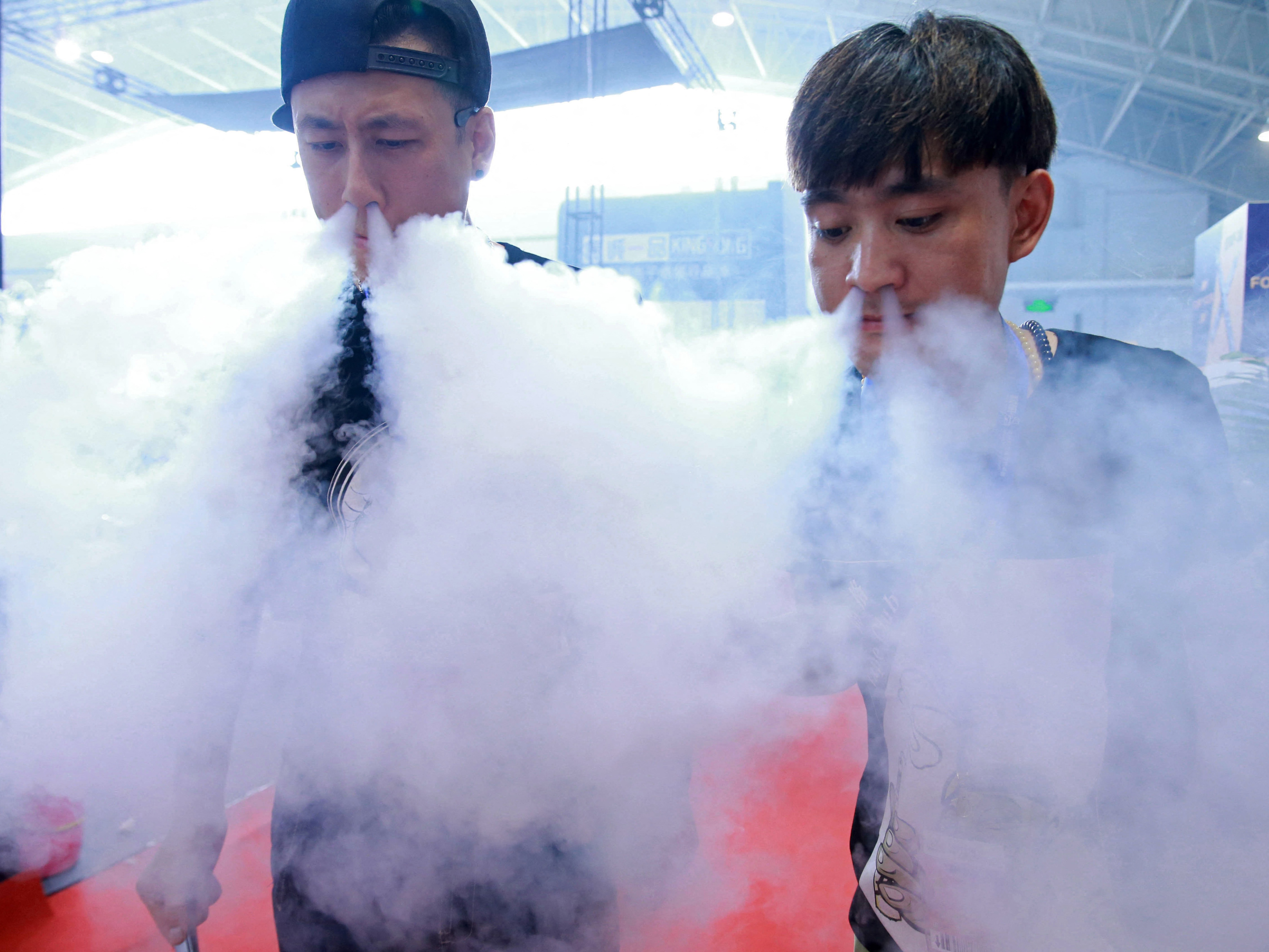 caption: Sales staff demonstrate vaping at a vape expo in Beijing, China.