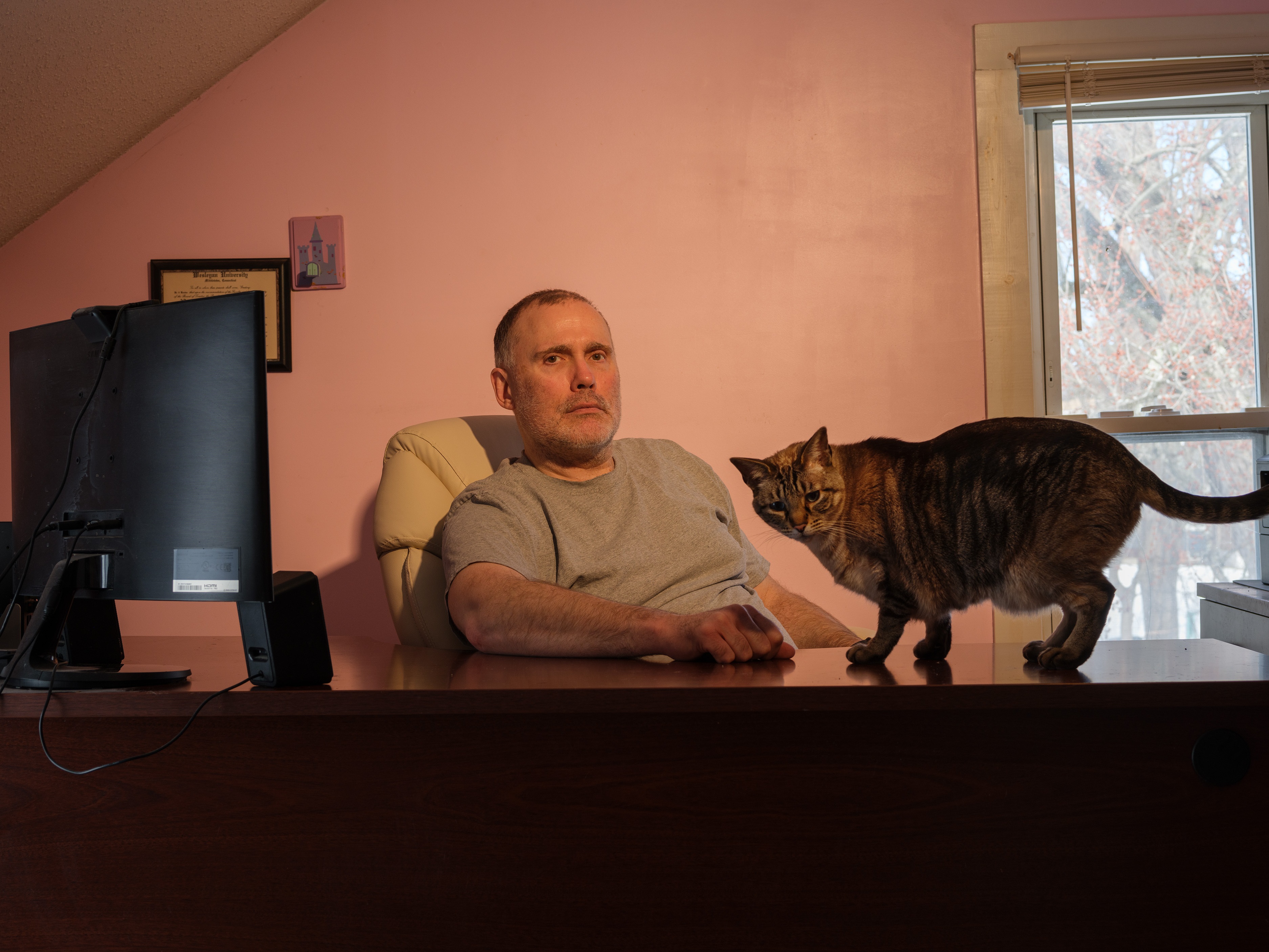 caption: Ken Warner sits with his cat Ostara in his home office in Manchester, Conn. where he writes sci-fi and fantasy novels. Warner and his wife, Parveen Vohra, who is a therapist, buy their insurance on HealthCare.gov.