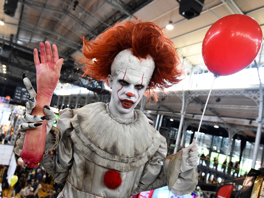 caption: A cosplayers dressed as Pennywise from "It" poses during the Comic Con festival in 2017 at the Grande Halle de la Villette in Paris.