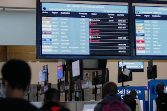caption: Travelers walk near an electronic flight notice board displaying canceled flights at O.R. Tambo International Airport in Johannesburg, South Africa, on Saturday. Several countries have begun travel bans in response to the omicron variant.