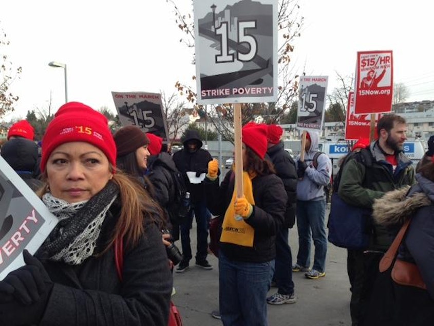 caption: FILE: Fast-food workers and minimum wage advocates marched from SeaTac to Seattle in December 2013 as part of a national demonstration for a $15 minimum wage.