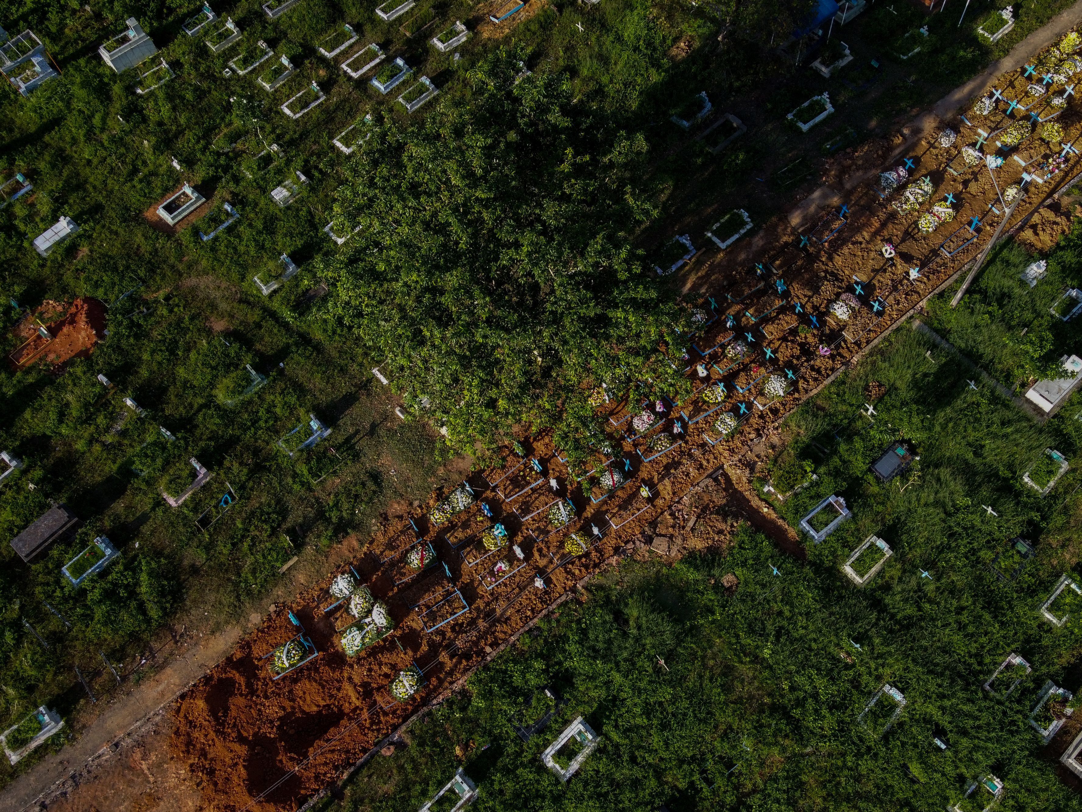caption: With little space left at Nossa Senhora Aparecida cemetery in Manaus, Brazil, graves of COVID-19 victims line a street, seen in an aerial photo taken on Thursday as the country passed 400,000 virus deaths.