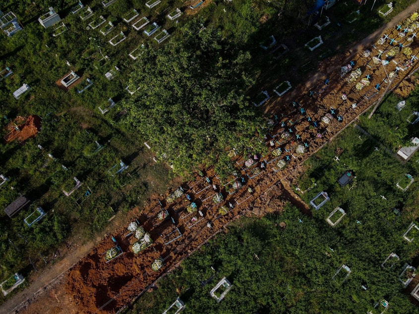 caption: With little space left at Nossa Senhora Aparecida cemetery in Manaus, Brazil, graves of COVID-19 victims line a street, seen in an aerial photo taken on Thursday as the country passed 400,000 virus deaths.