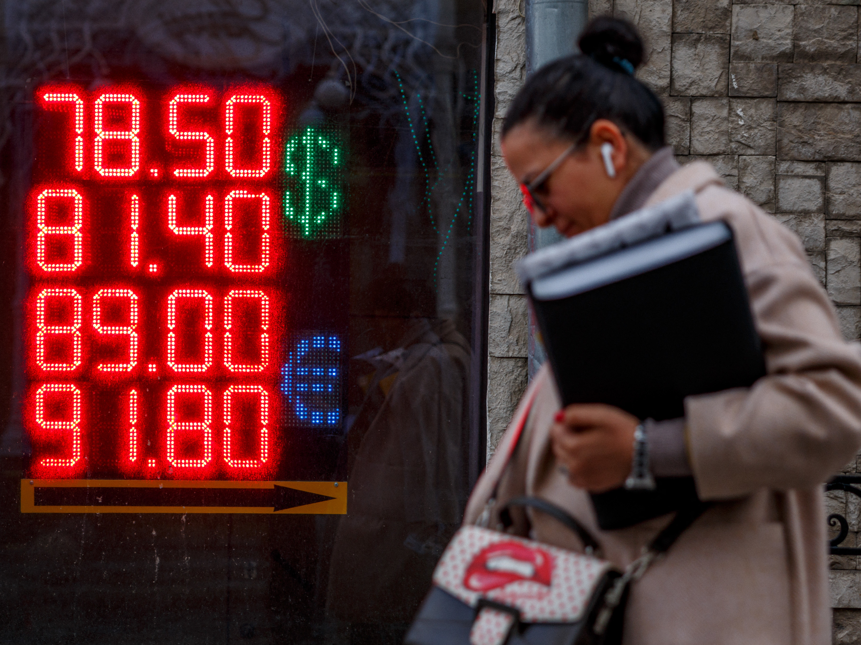 caption: A woman walks past a board showing currency exchange rates of the U.S. dollar and the euro against Russian ruble in Moscow on Feb. 22. Russia owes over $100 million in interest rate payments for two bonds on Wednesday as fears grow the country will default on its debt.