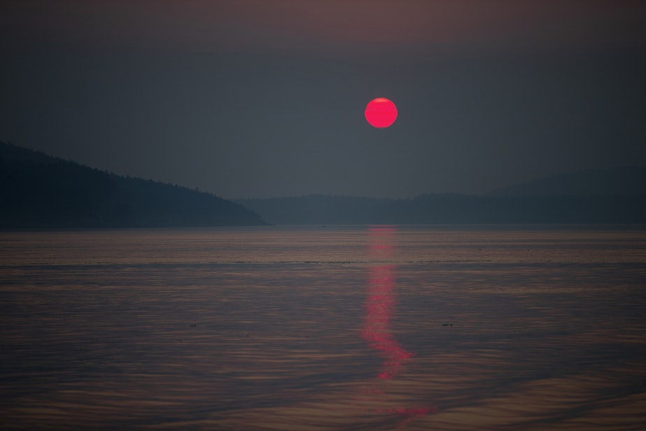 caption: A smokey sunrise over the Salish Sea is shown on Sunday, August 27, 2023, as seen from a Washington state ferry headed for San Juan Island. 