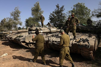 caption: Israeli soldiers gather around tanks lined up in southern Israel near the border with Gaza on Sunday amid a cease-fire following weeks of battles between Israel and Palestinian Hamas militants.