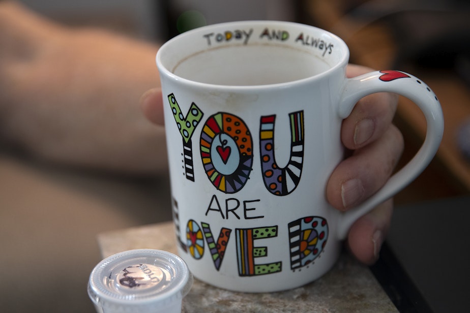 caption: 'You are loved' reads Allan Opie's coffee mug, on Thursday, October 19, 2023, at their home in Cashmere. Opie's daughter, Rita Cooper, has been caring for him for the last three years.