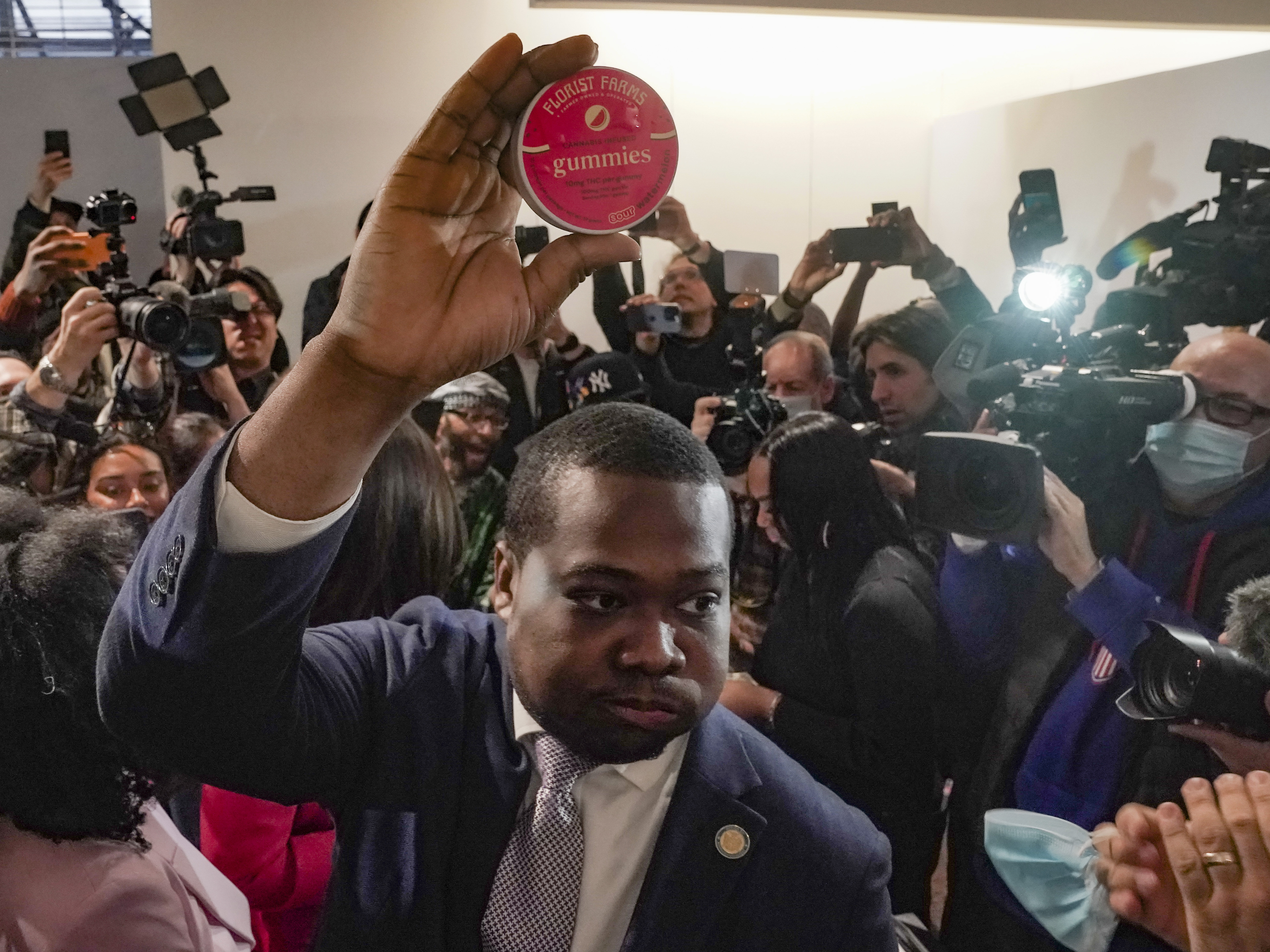 caption: Chris Alexander, executive director of the New York State Office of Cannabis Management, shows off the first purchase of cannabis gummies bought at Housing Works — New York's first legal cannabis dispensary, during a press conference to kick-off its opening on Thursday.