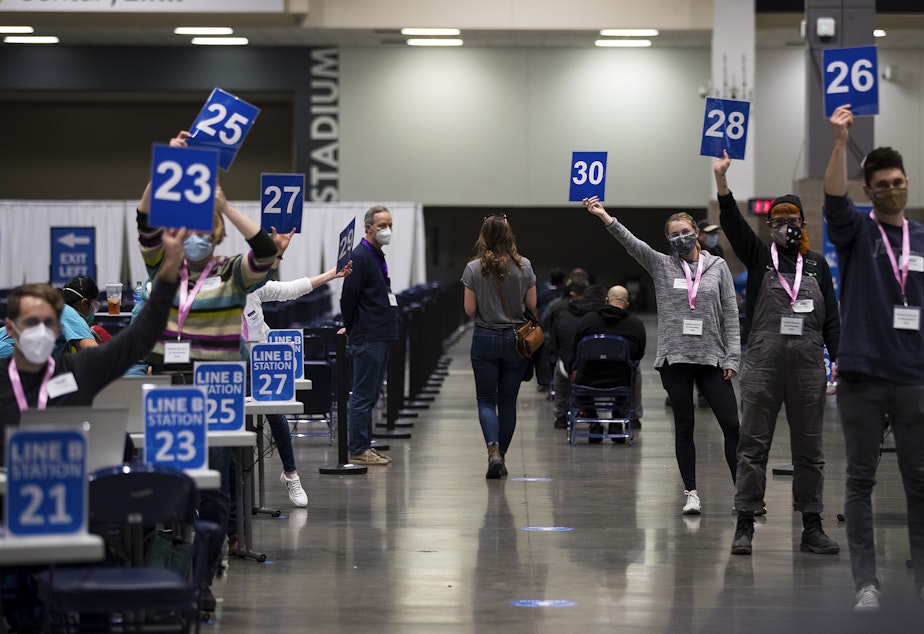 caption: Volunteers call for patients at the new civilian-led mass Covid-19 vaccination site on Saturday, March 13, 2021, at Lumen Field Event Center in Seattle.