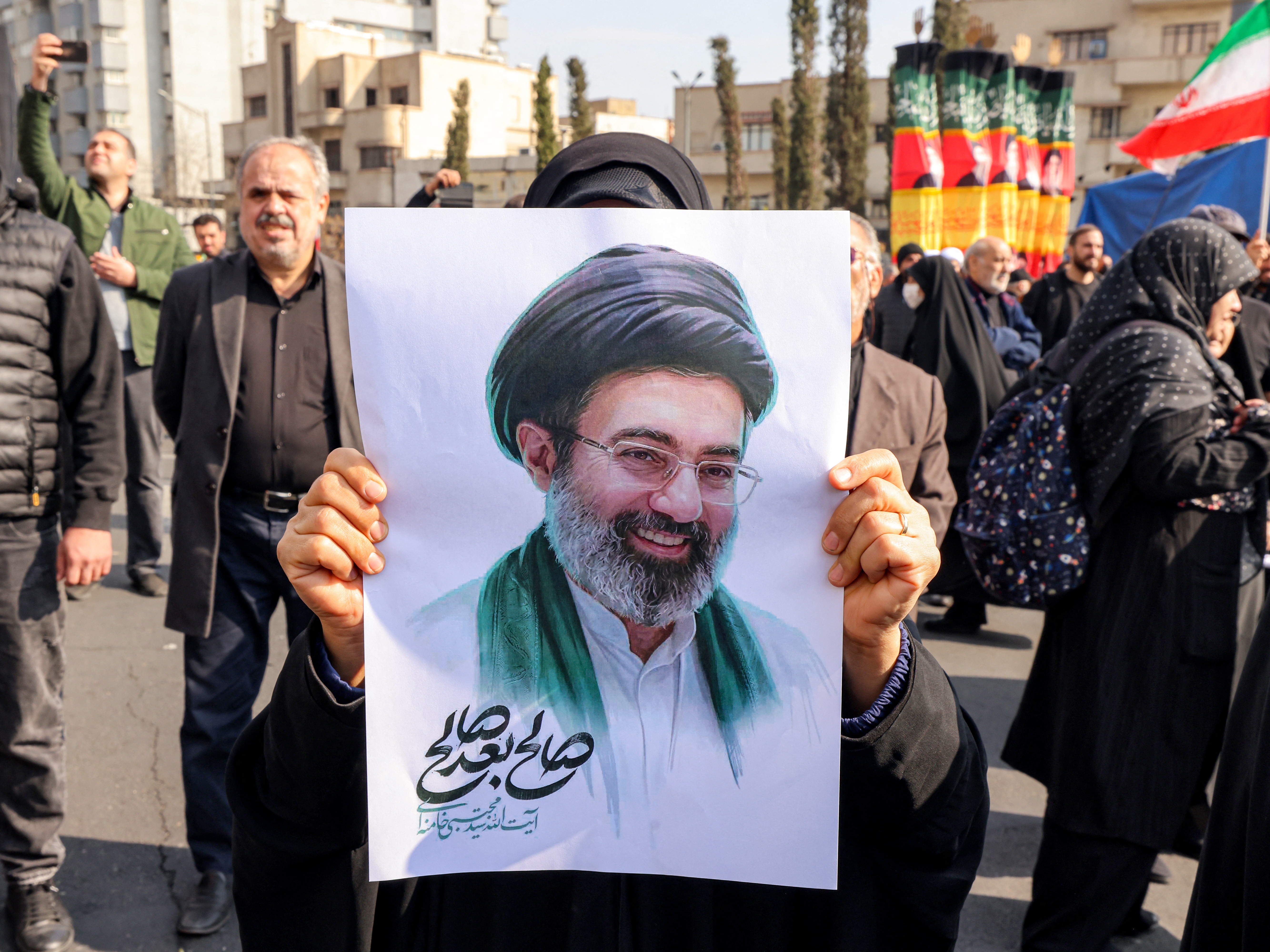 caption: A supporter poses with a picture of Iran's new supreme leader, Mojtaba Khamenei, during a rally in central Tehran on Monday.
