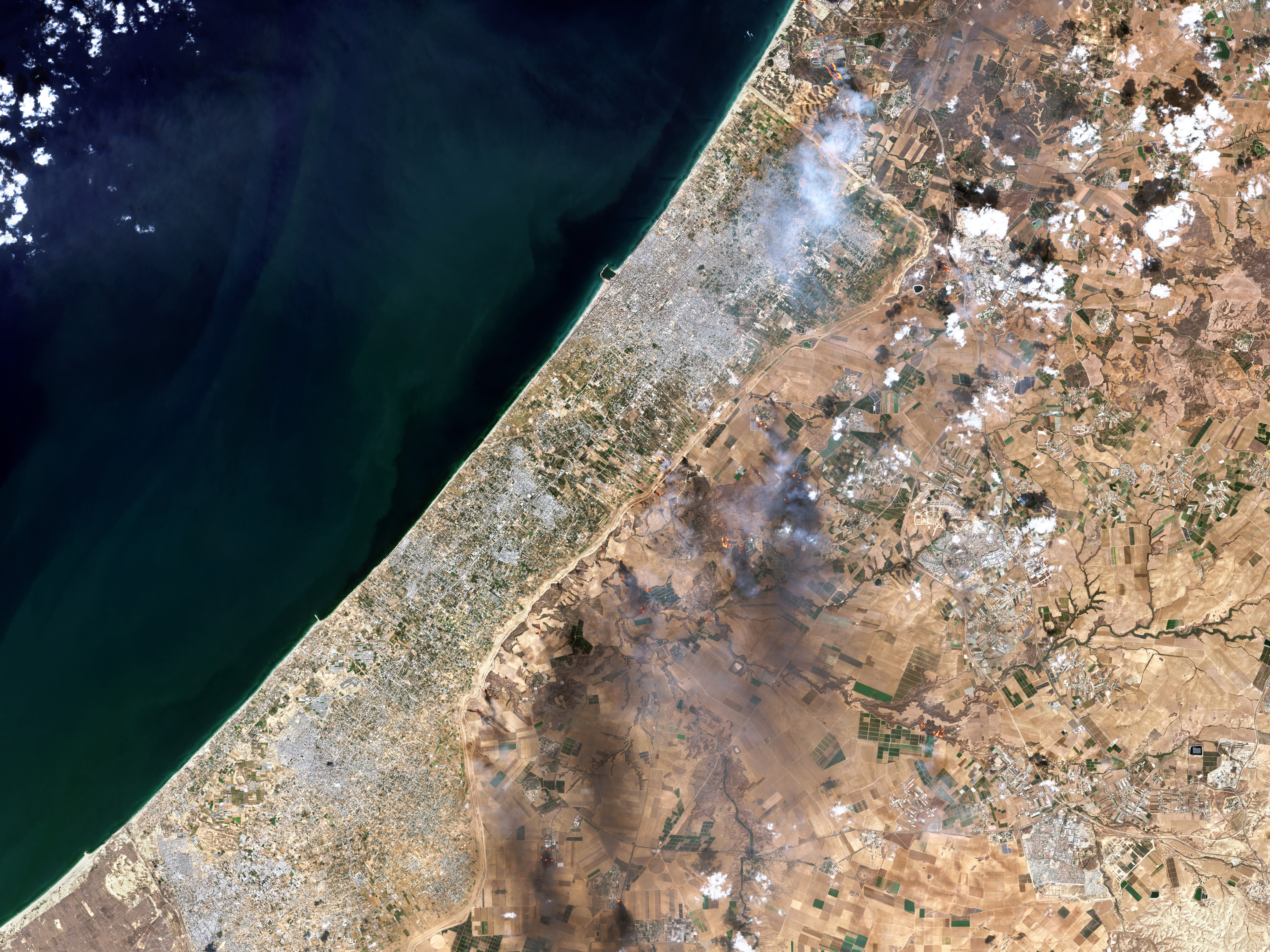 caption: A satellite view shows smoke along the Gaza-Israel border on Oct. 7 in an image combining natural with shortwave-infrared highlights. The image came from a Copernicus Sentinel satellite run, by the EU space program.