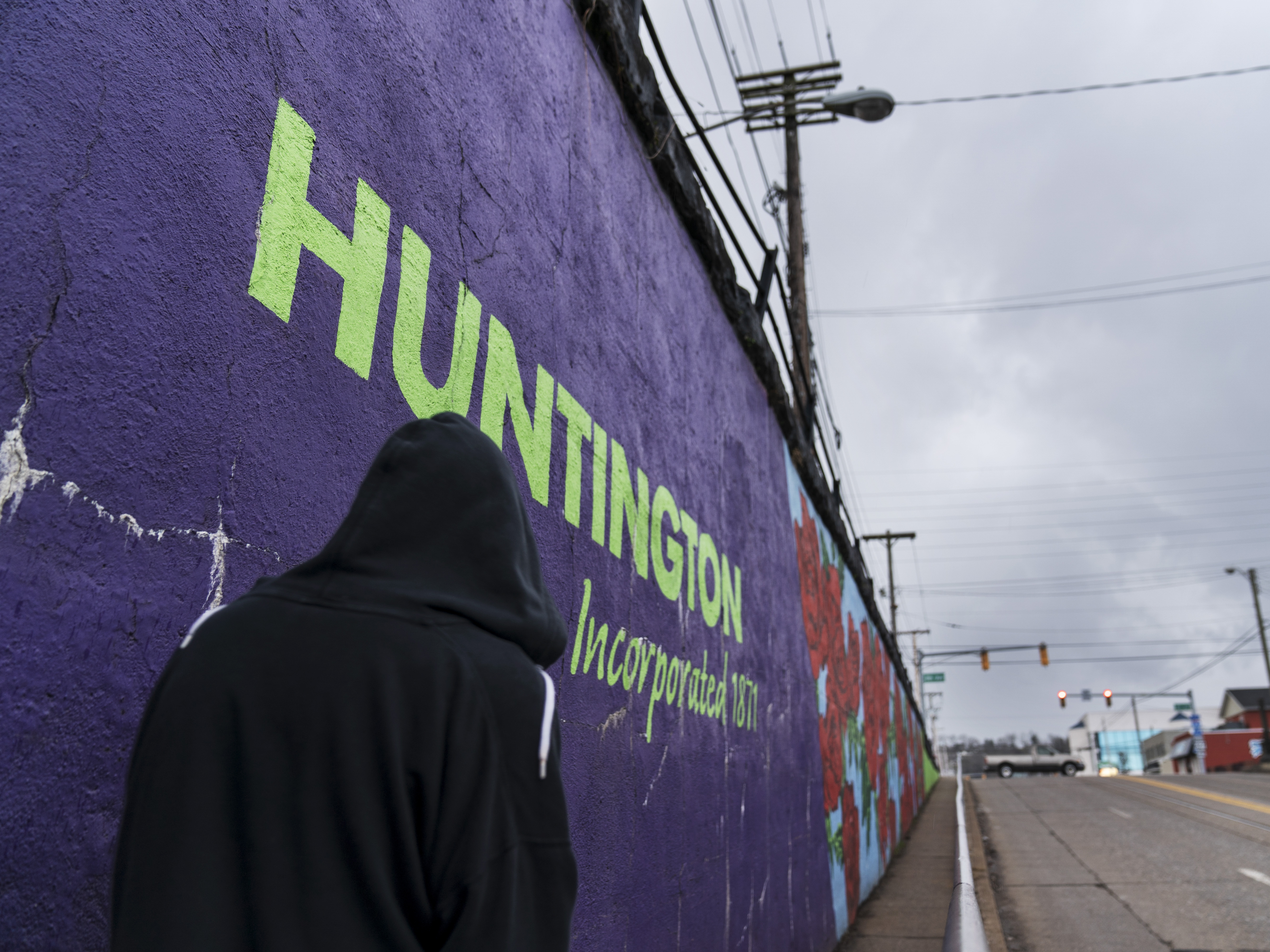 caption: A pedestrian walks past a mural in Huntington, W.Va., on March 18. Huntington was once ground zero for the U.S. opioid epidemic.