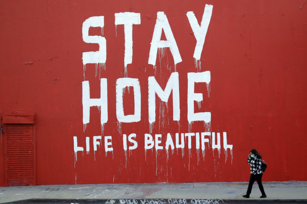caption: A pedestrian walks past a mural which reads "Stay at Home, Life is Beautiful" Thursday, April 2, 2020, in Los Angeles. (Marcio Jose Sanchez/AP Photo)