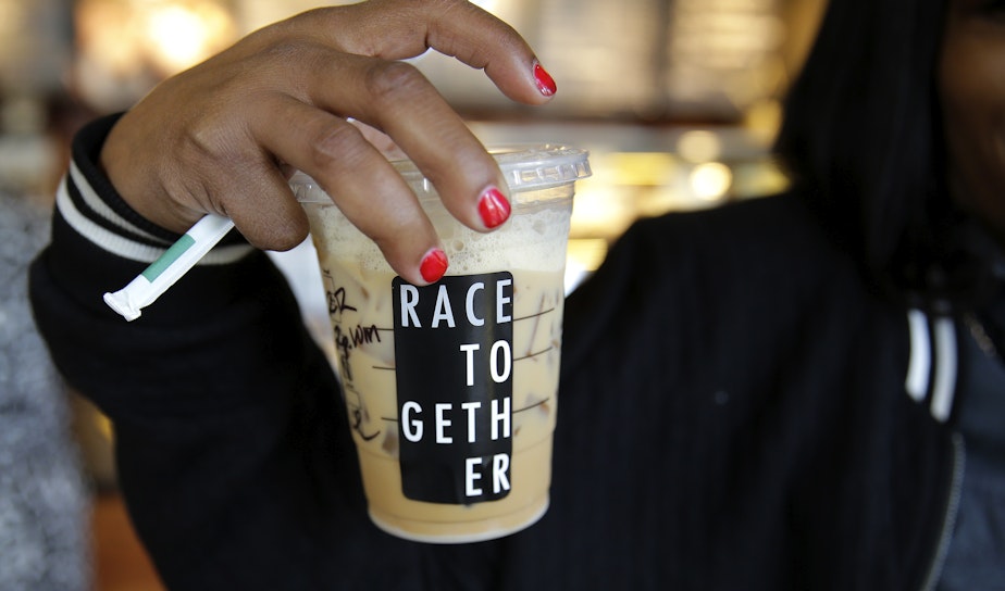 caption: Larenda Myres holds an iced coffee drink with a "Race Together" sticker on it at a Starbucks store in Seattle, Wednesday, March 18, 2015. 