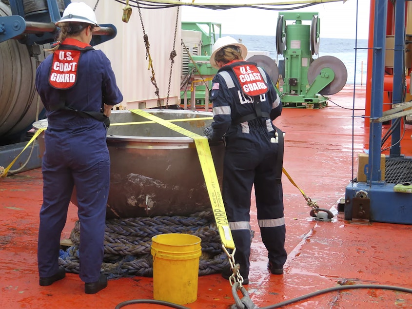 caption: In this photo provided by the U.S. National Transportation Safety Board, U.S. Coast Guard marine safety engineers survey the aft titanium endcap from the Titan submersible, in the North Atlantic Ocean in October 2023.