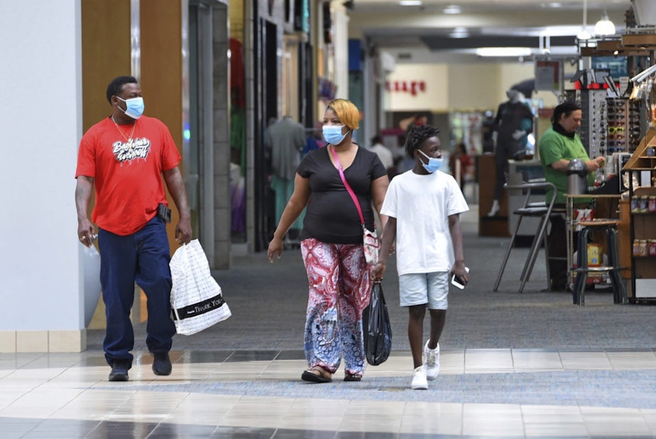 caption: Ronnie Johnson, left, Gwen Evans, center, and Jamarion Davis shop while wearing masks to protect against coronavirus,  after the Anderson Mall opened to limited business, Friday, April 24 2020 in Anderson, S.C. (Richard Shiro/AP Photo)