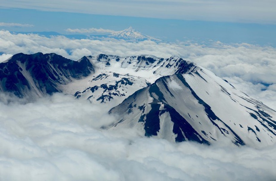 caption: <p>The plane got a good view of Mount St. Helens peeking through the clouds with&nbsp;Mount Hood in the background.</p>