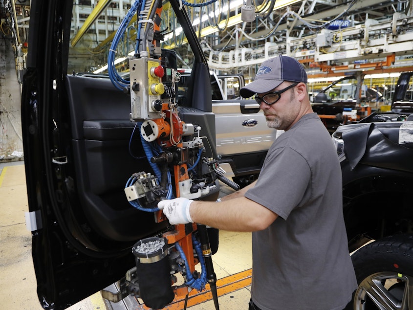 caption: A worker installs a door on a 2018 Ford F-150 truck at an assembly plant in Dearborn, Mich., on Sept. 27. The U.S. unemployment rate fell to 3.7 percent, a nearly 50-year low.