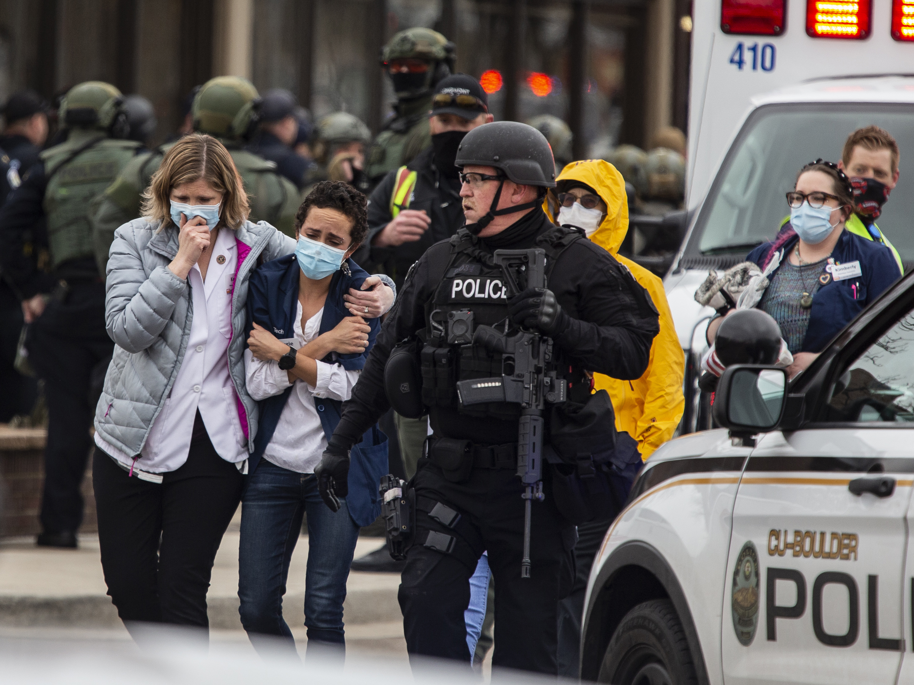 caption: Healthcare workers walk out of a King Sooper's Grocery store after a gunman opened fire on Monday in Boulder, Colo.
