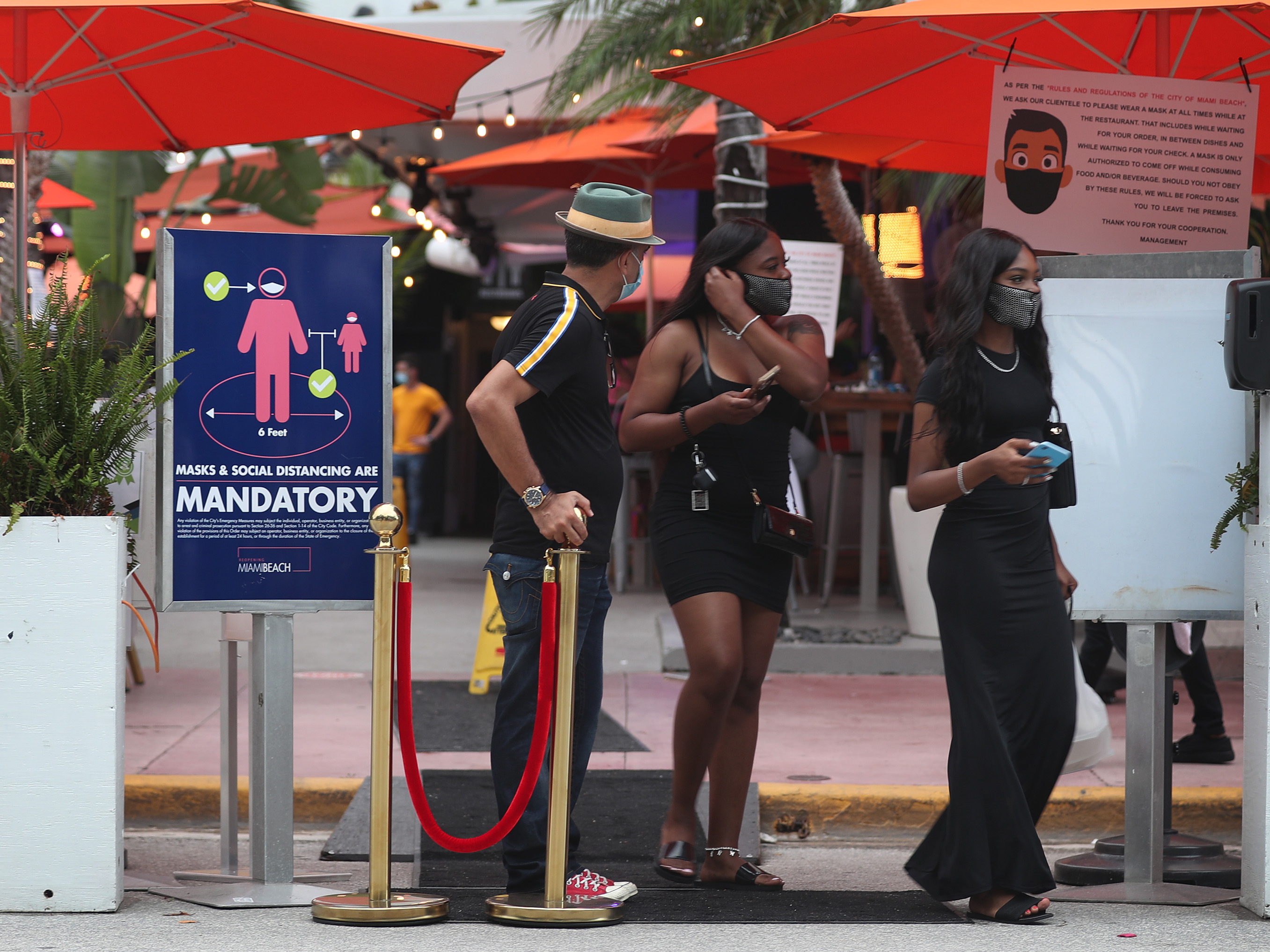 caption: People leave the Ocean 10 restaurant as a curfew from 8 p.m. to 6 a.m. is put in place on Saturday in Miami Beach, Fla.