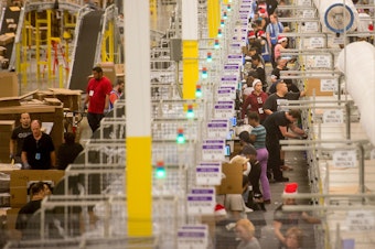 caption: Amazon says it will pay all its U.S. workers at least $15. Here, workers prepare shipments at an Amazon Fulfillment Center in California during the early Christmas rush in 2014.