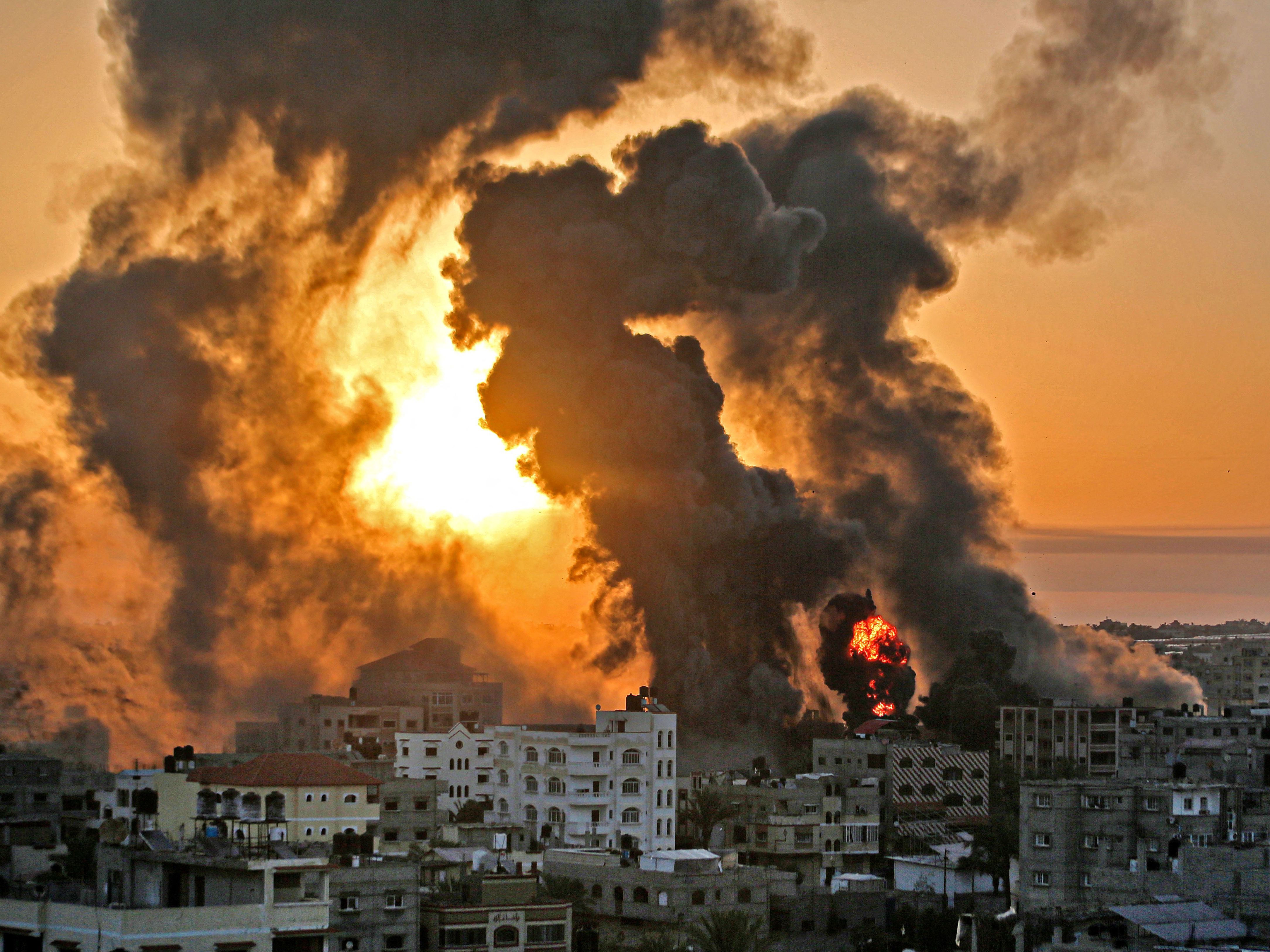 caption: A fire rages at sunrise in the city of Khan Yunis following an Israeli airstrike in the southern Gaza Strip early on May 12.