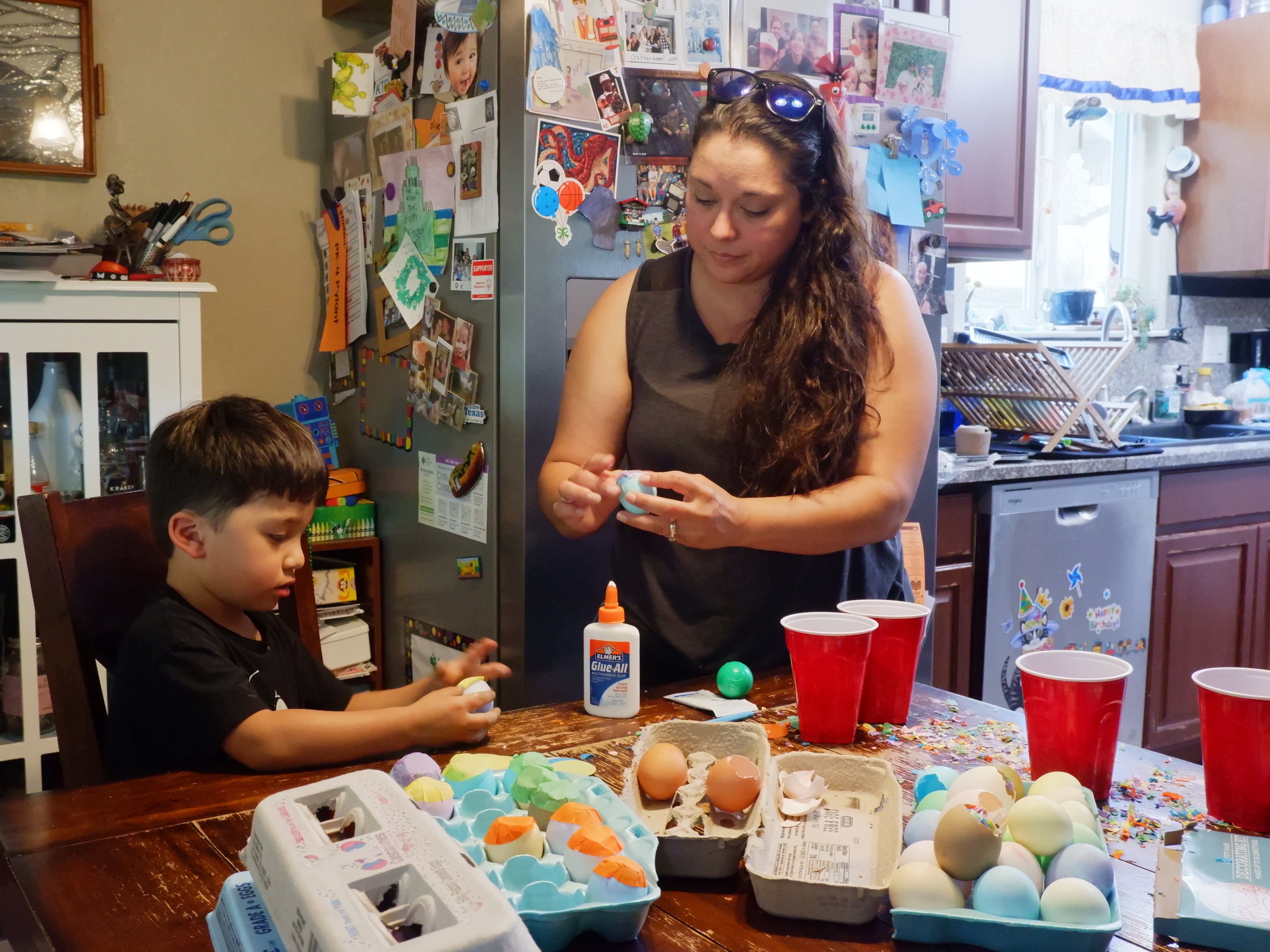 caption: Denise Solis shows her four-year-old son Noah Solis how to seal a cascaron (confetti-filled egg) with tissue paper.