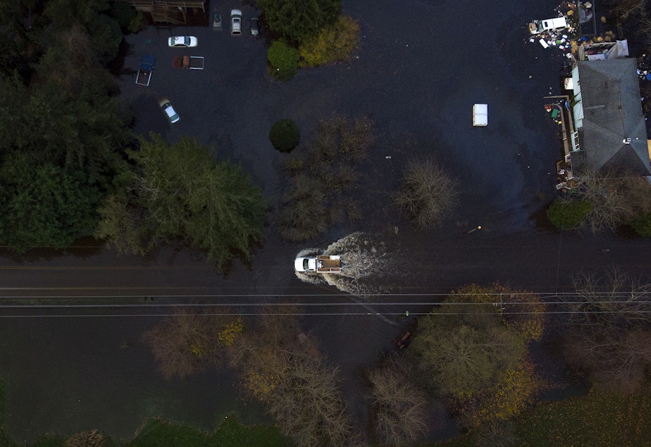 caption: A truck drives through a flooded stretch of Old Day Creek Road on Tuesday, November 16, 2021, in Clear Lake, Washington.