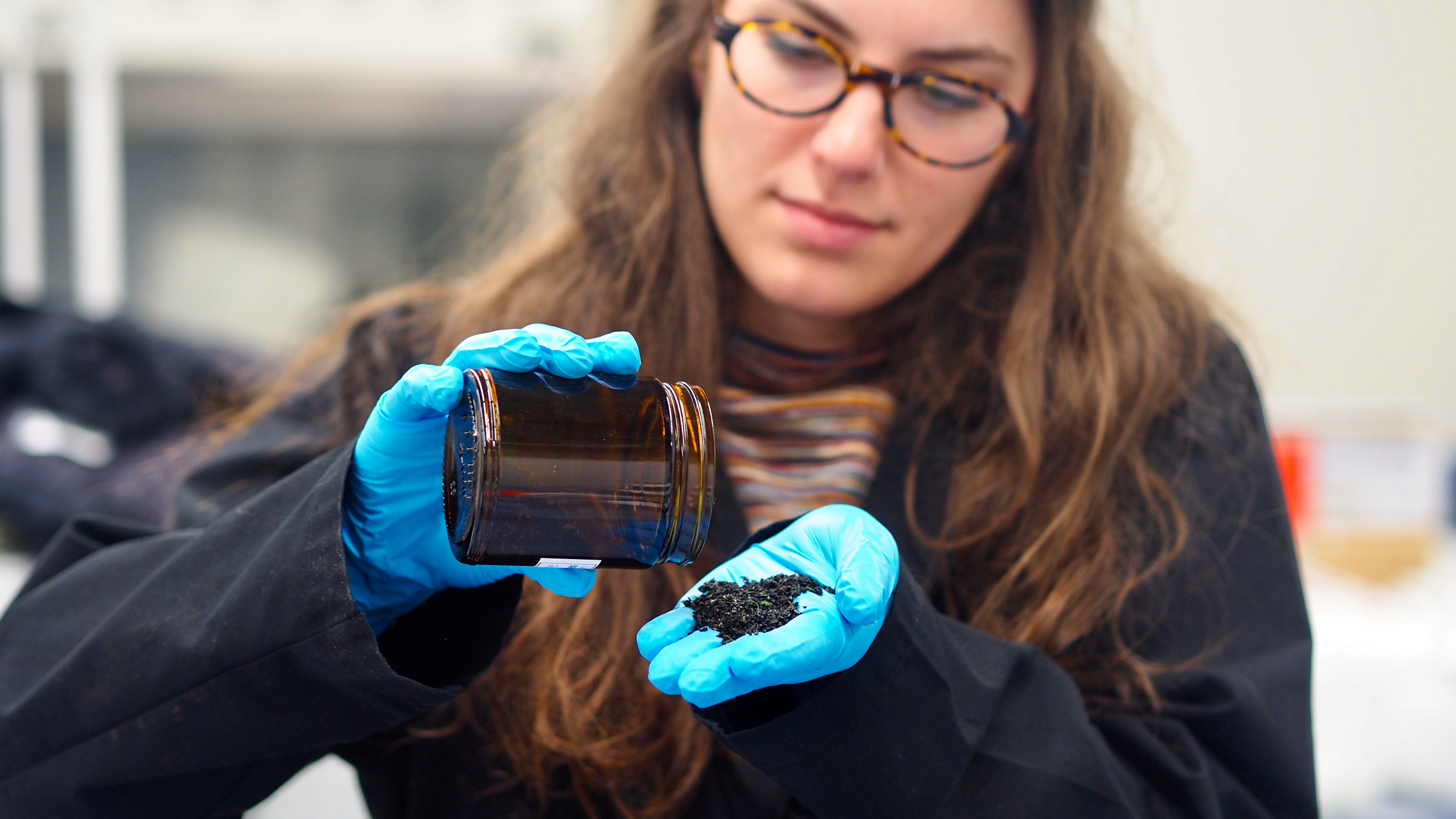 caption: Katie Moloney, a doctoral student in civil engineering at the University of British Columbia, examines crumb rubber particles collected for research examining the impact of tire chemicals on coho-rearing streams in Vancouver. 