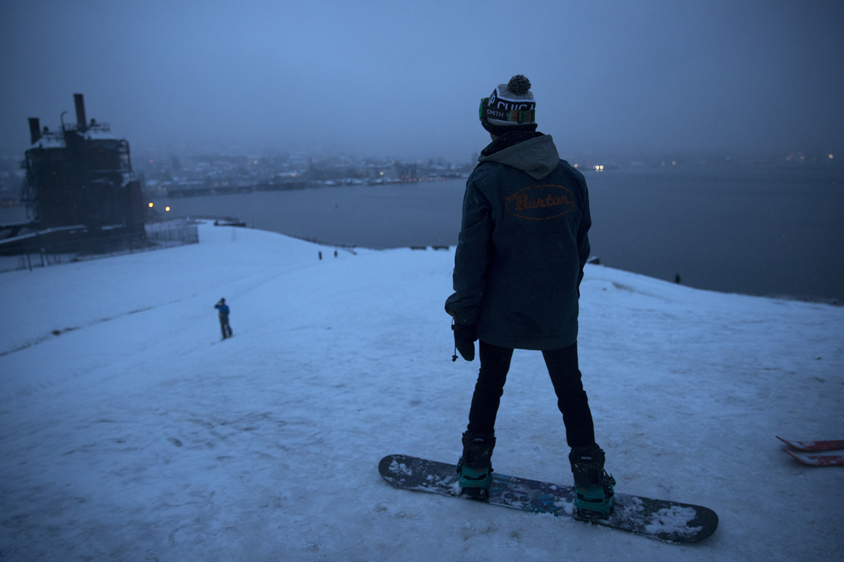 caption: Alec Pflaster gets ready to snowboard down the hill on Monday, February 11, 2019, at Gas Works Park in Seattle. 