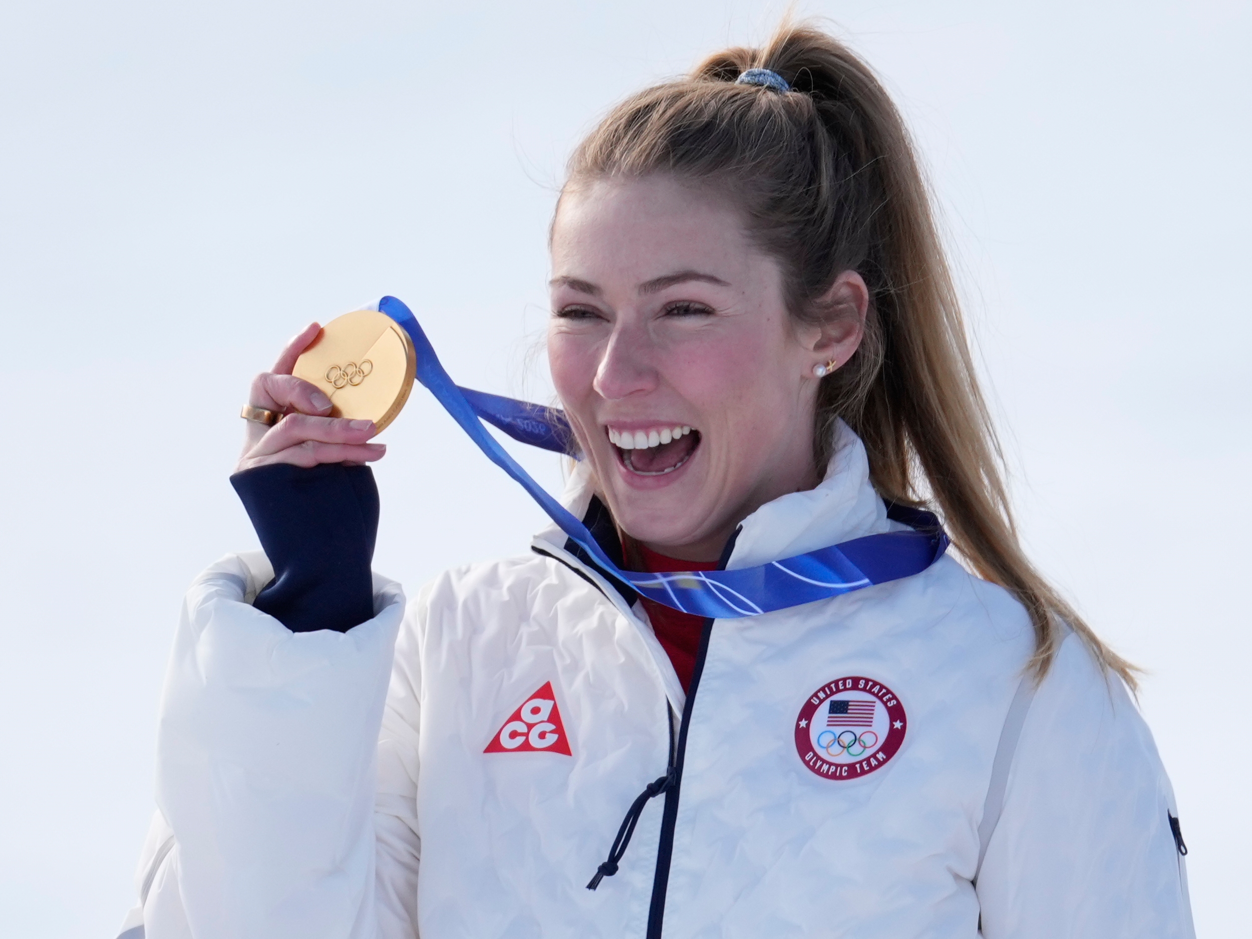 caption: Mikaela Shiffrin from Colorado shows her gold medal for the Alpine ski, women's slalom race at the 2026 Winter Olympics, in Cortina d'Ampezzo, Italy, on Wednesday.