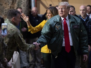 caption: President Trump and first lady Melania Trump arrive to speak to members of the U.S. military during an unannounced trip to Al Asad Air Base in Iraq on Dec. 26.