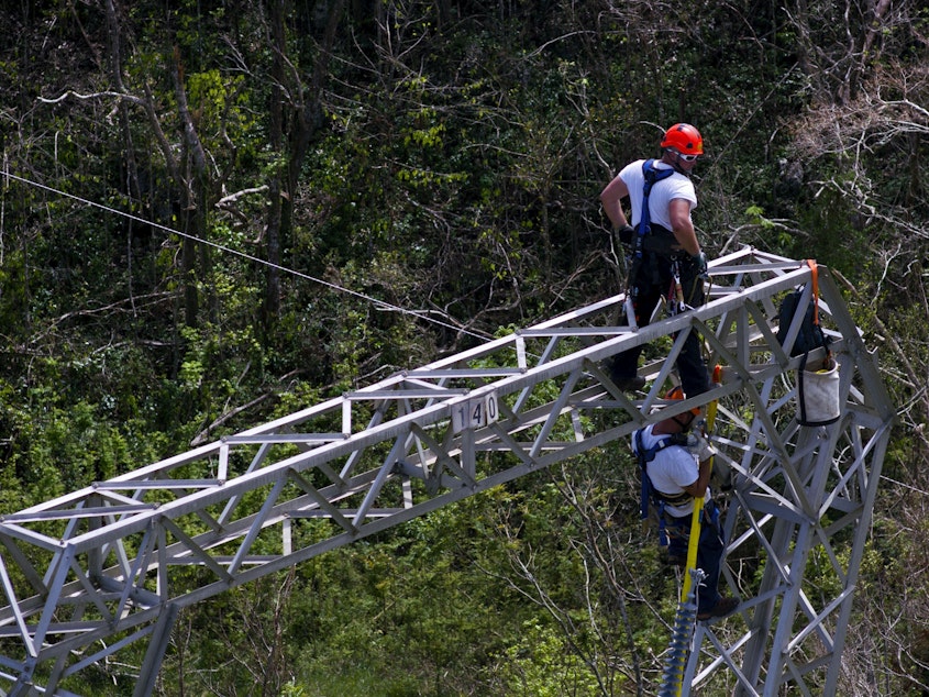 caption: Workers restore power lines damaged by Hurricane Maria in Barceloneta, Puerto Rico, in 2017. The Trump administration announced it will award nearly $13 billion in infrastructure grants to help the island recover from the storm.
