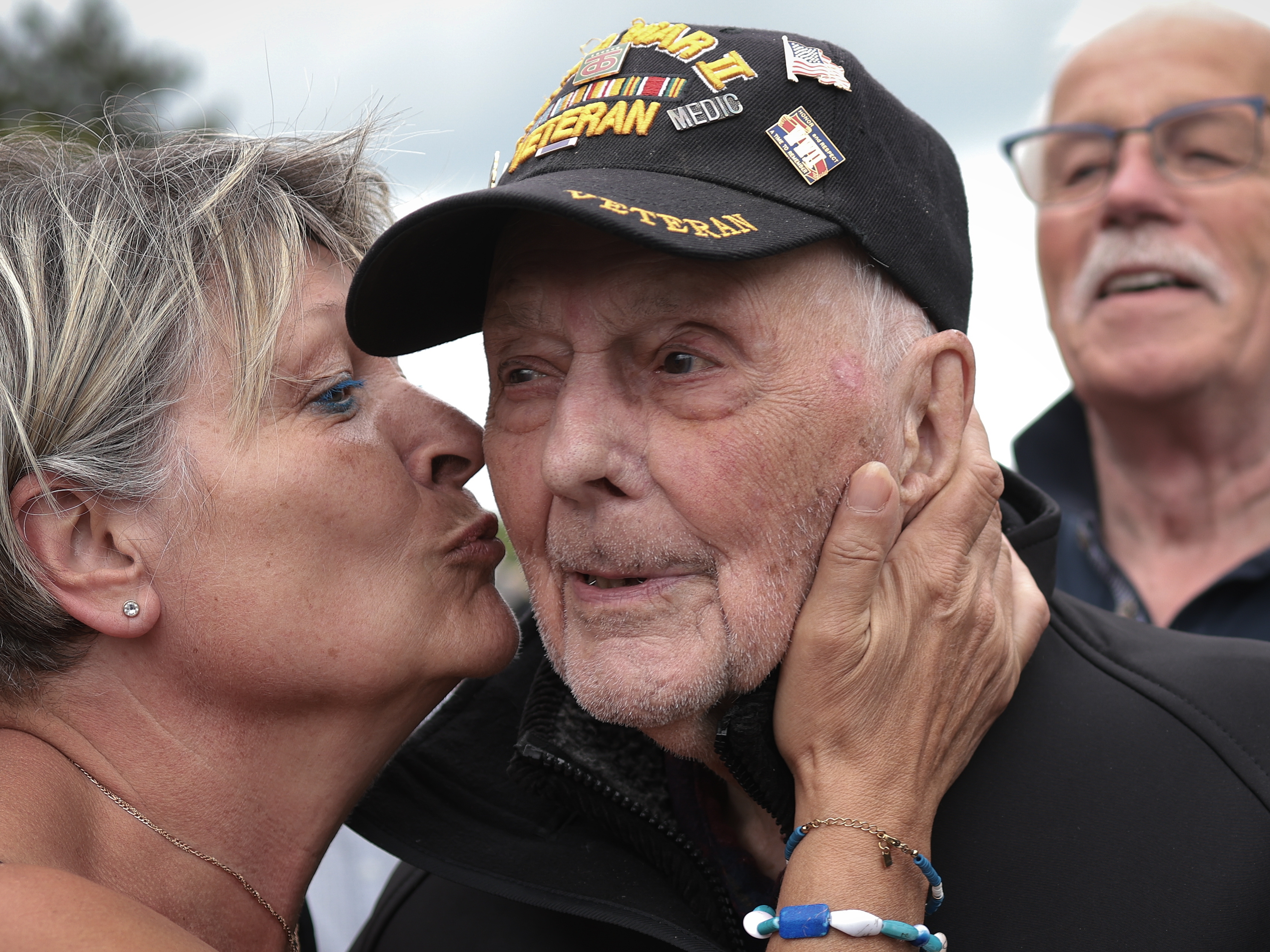 caption: World War II veteran Gene Kleindl, age 102, from Rockford, Ill., receives a kiss from Chantell Boivin while leaving the Normandy American Cemetery on June 4 in Colleville-sur-Mer, France. Kleindl, a medic in the U.S. Army's 90th Infantry Division, arrived on the beaches of Normandy on D-Day.