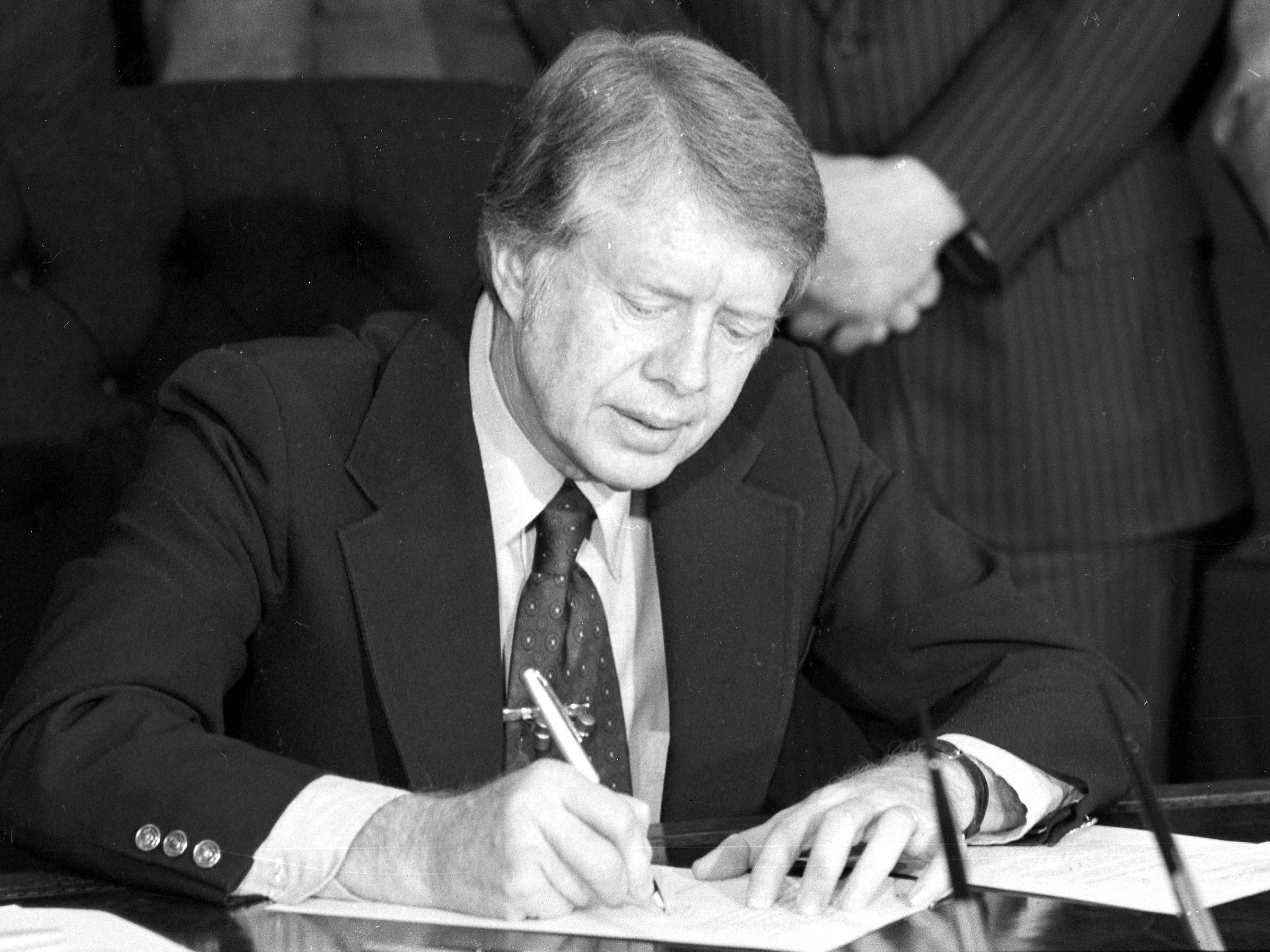 caption: President Jimmy Carter signs an emergency natural gas legislation in the Oval Office of the White House in Washington, D.C., in 1977.