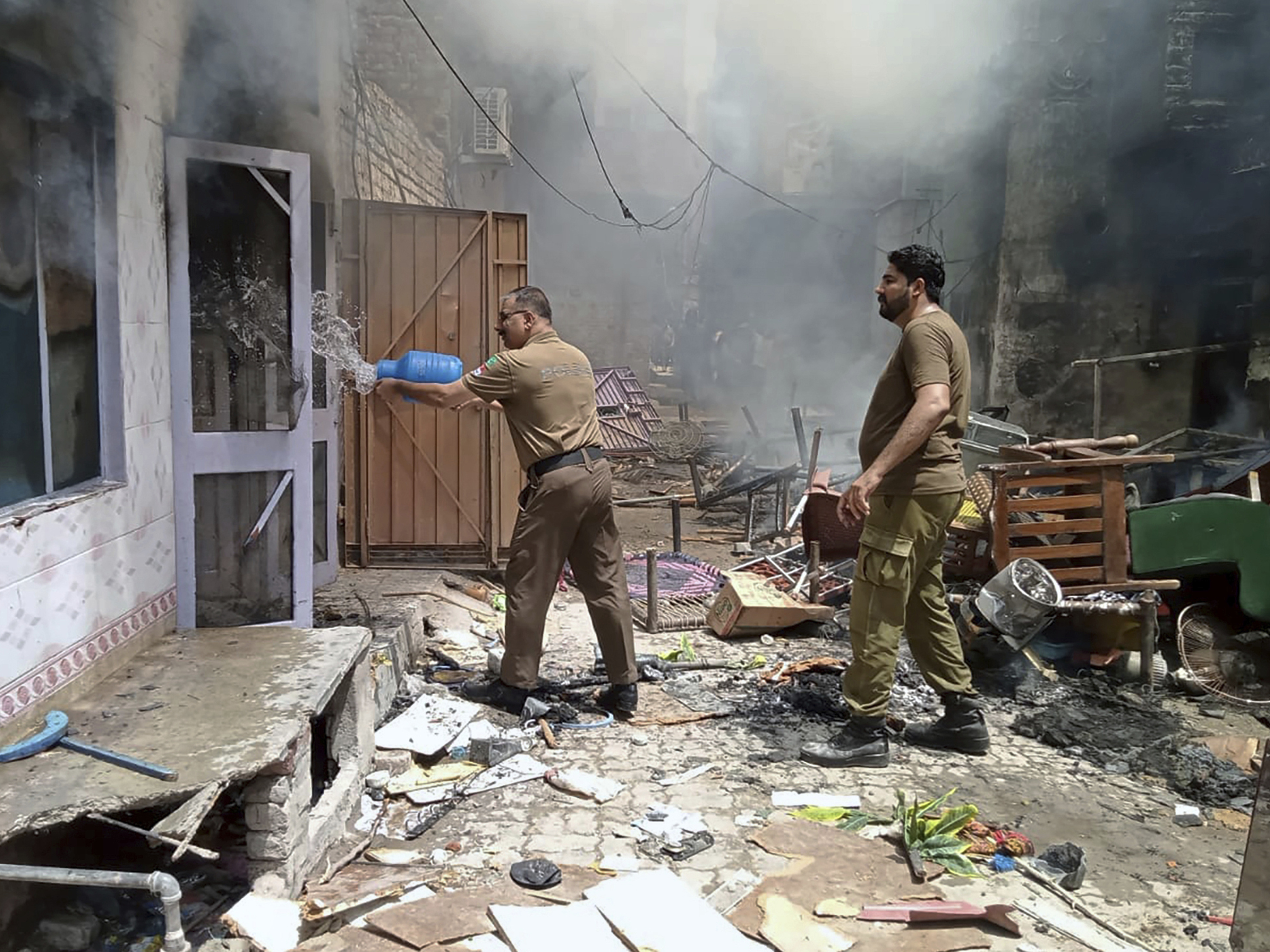 caption: In this photo provided by district police office, a police officer pours water into a burning house in a Christian neighborhood in Jaranwala, near Faisalabad, Pakistan, Wednesday. A mob burned a church and damaged at least four others, police and local Christians said. The mob also demolished a man's house after accusing him of desecrating Islam's holy book, and attacked other Christian homes.
