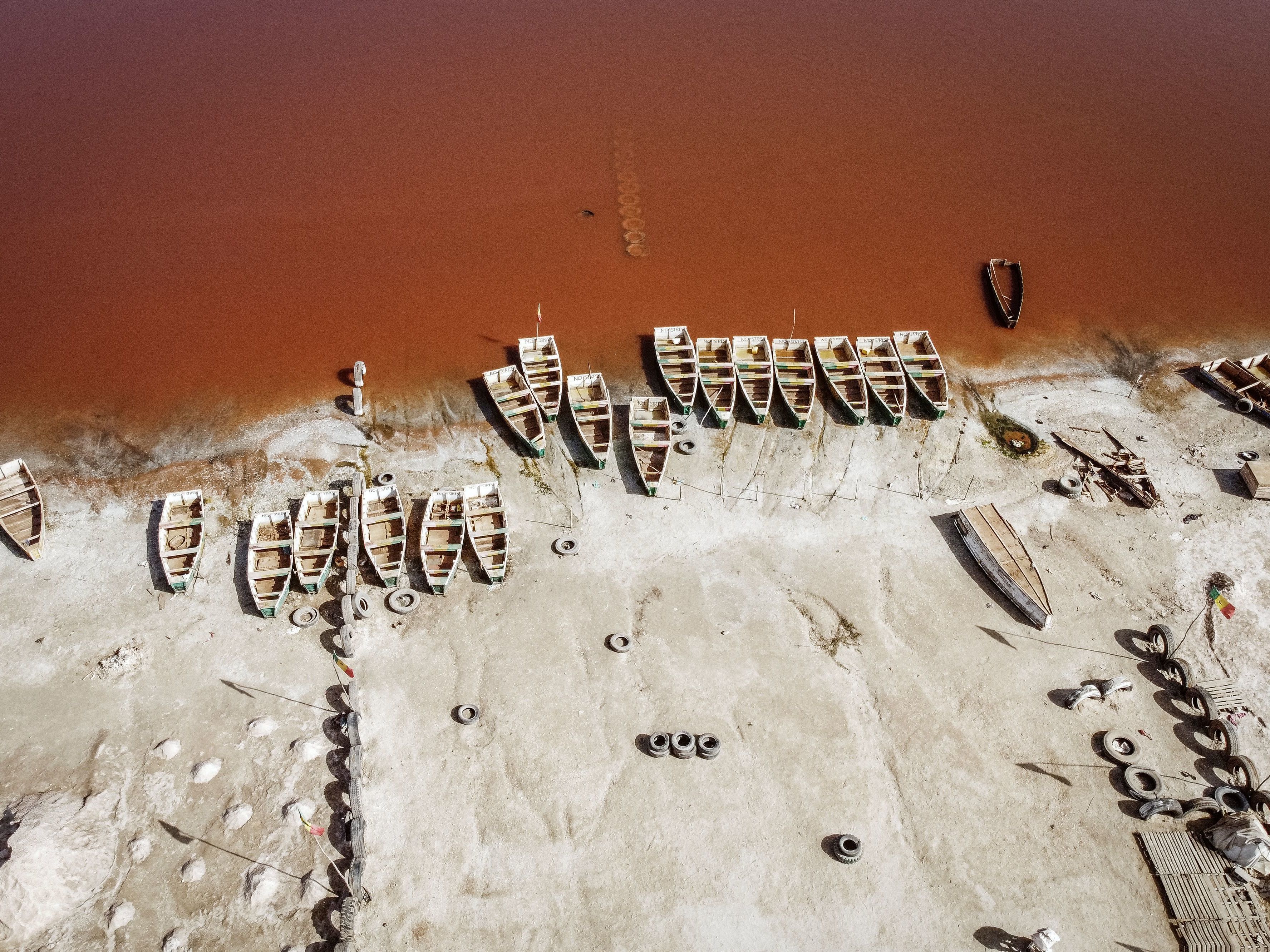 caption: This areal view shows rows of boats used for harvesting salt in Lake Retba in Senegal in 2021.