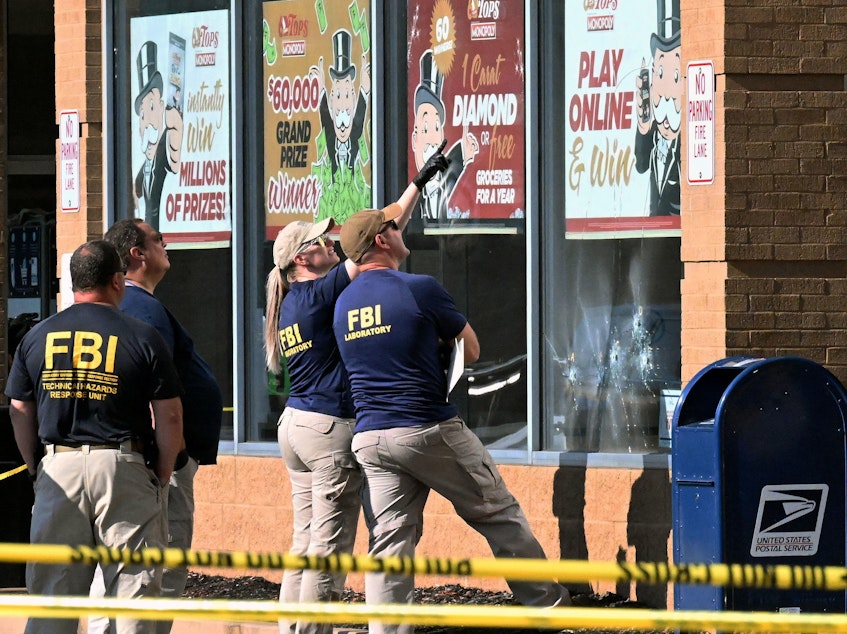 caption: FBI agents look at bullet impacts in a Tops grocery store in Buffalo, New York on Sunday, a day after a gunman shot dead 10 people.