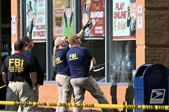 caption: FBI agents look at bullet impacts in a Tops grocery store in Buffalo, New York on Sunday, a day after a gunman shot dead 10 people.