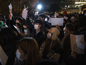 caption: Protesters hold up a white piece of paper against censorship during a protest against China's strict zero COVID measures on November 27, 2022 in Beijing.