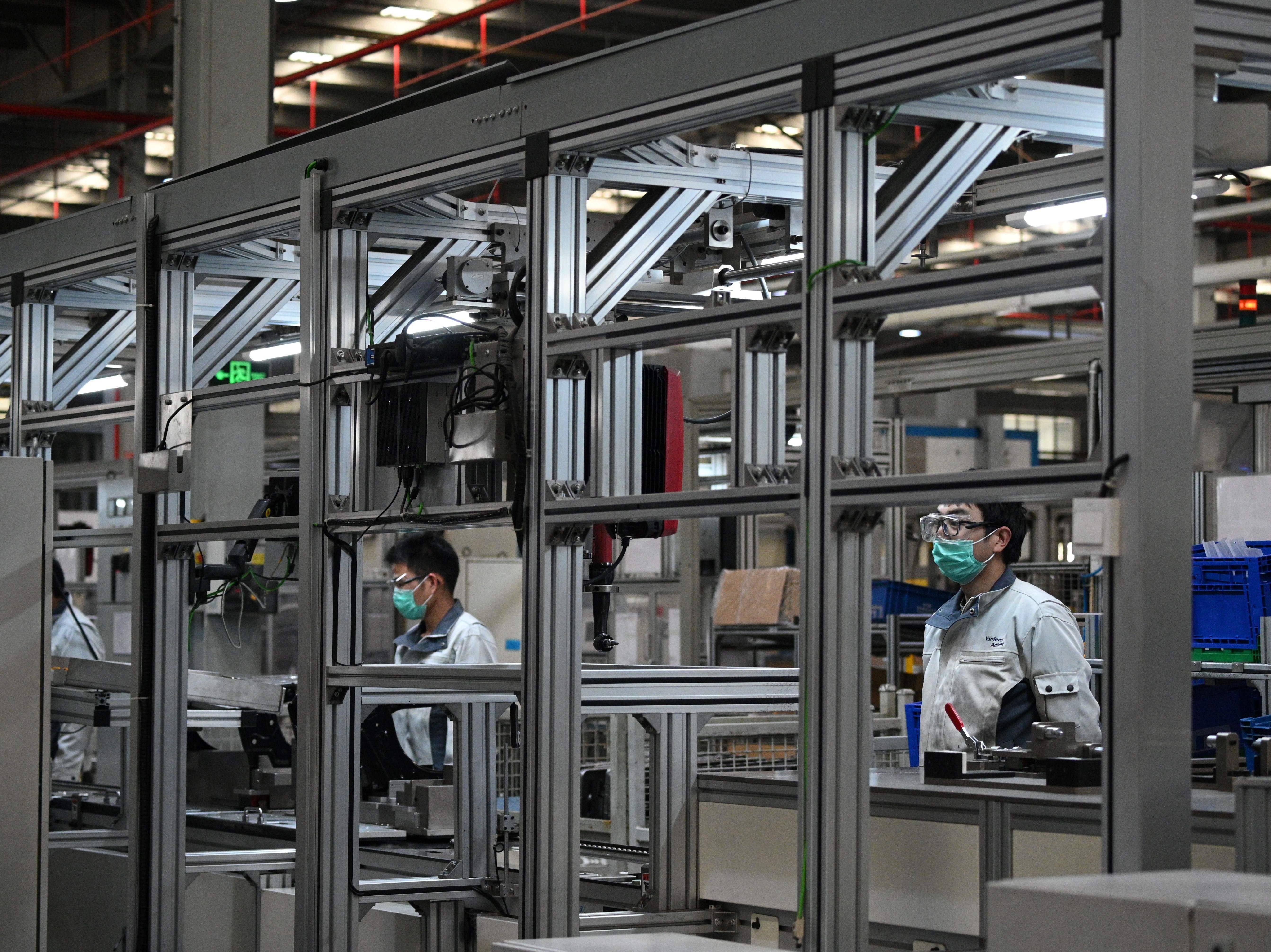 caption: Workers wear protective face masks at the Yanfeng Adient factory in Shanghai, where car seats are assembled, on Feb. 24.