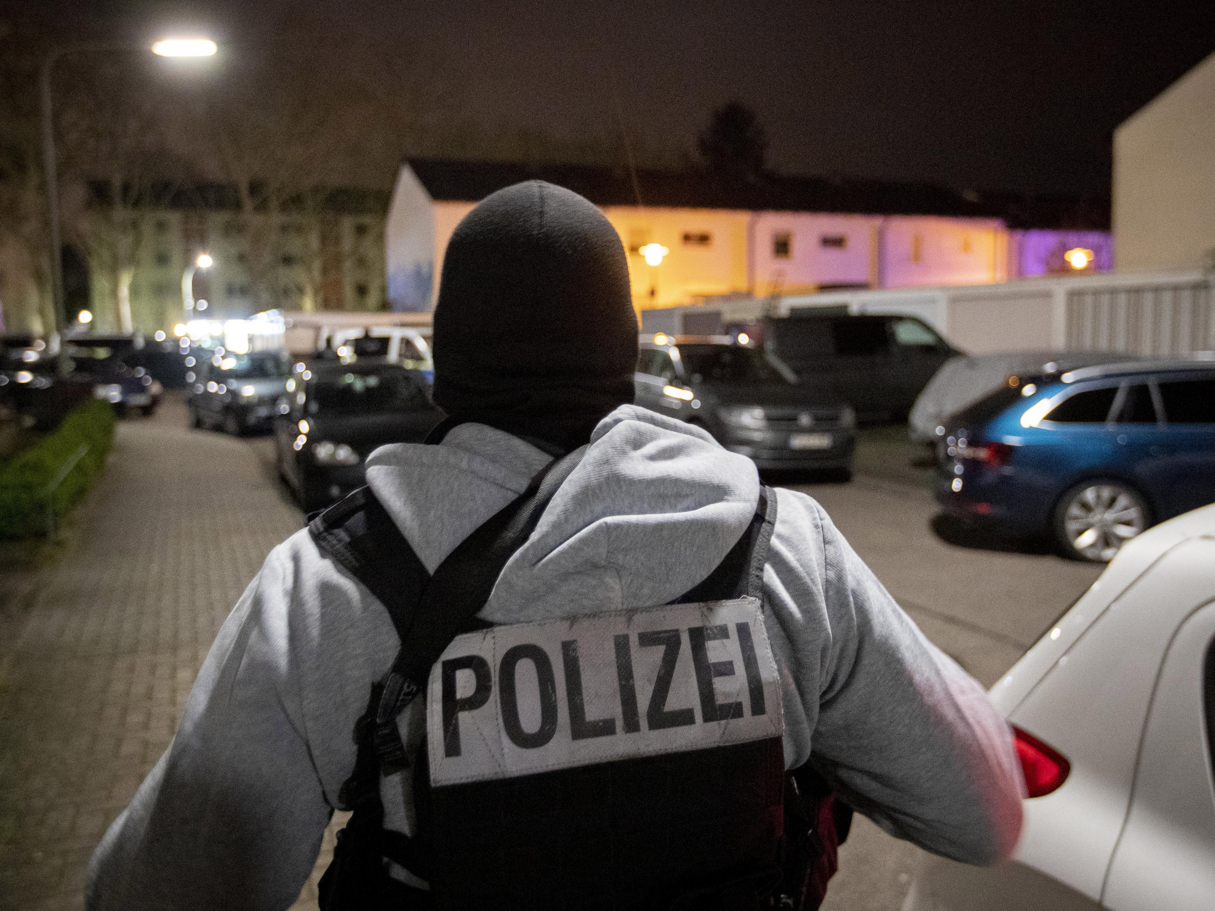 caption: A police officer guards the road in front of a house where police found the bodies of the suspected gunman and his mother, in Hanau, Germany, on Thursday.