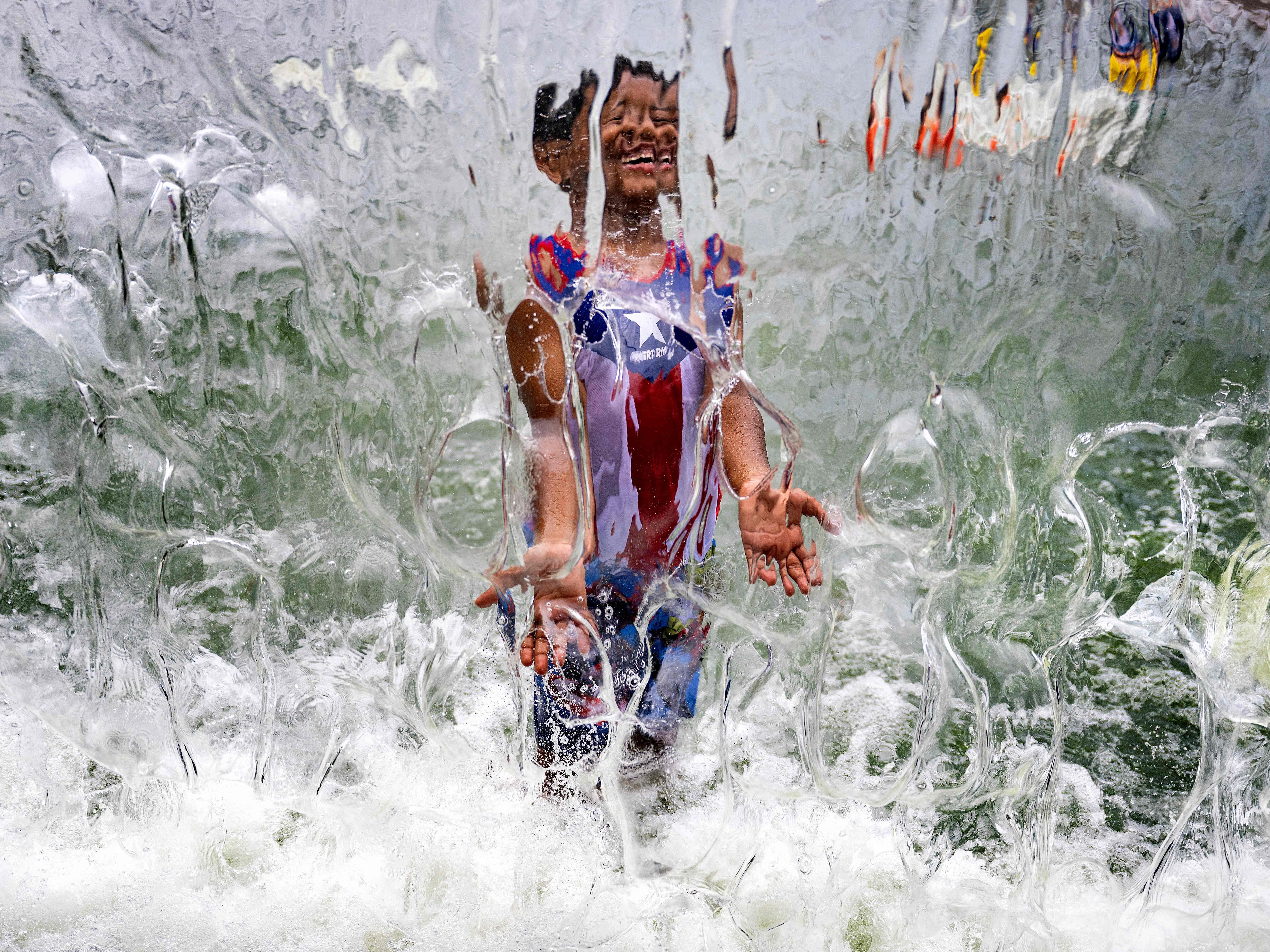 caption: A summer of extreme heat is raising alarms of health risks. Here, a child plays in a waterfall feature at Yards Park in Washington, D.C., on June 26.