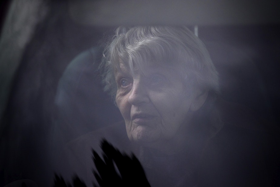 caption: Dorothy Campbell sits in her son's vehicle after knocking on her husband, Gene Campbell's window and speaking to him on the phone at the Life Care Center of Kirkland, the long-term care facility at the epicenter of the first coronavirus outbreak in the U.S., on Thursday, March 5, 2020, in Kirkland. There have been 46 deaths from Covid-19 associated with the facility. 