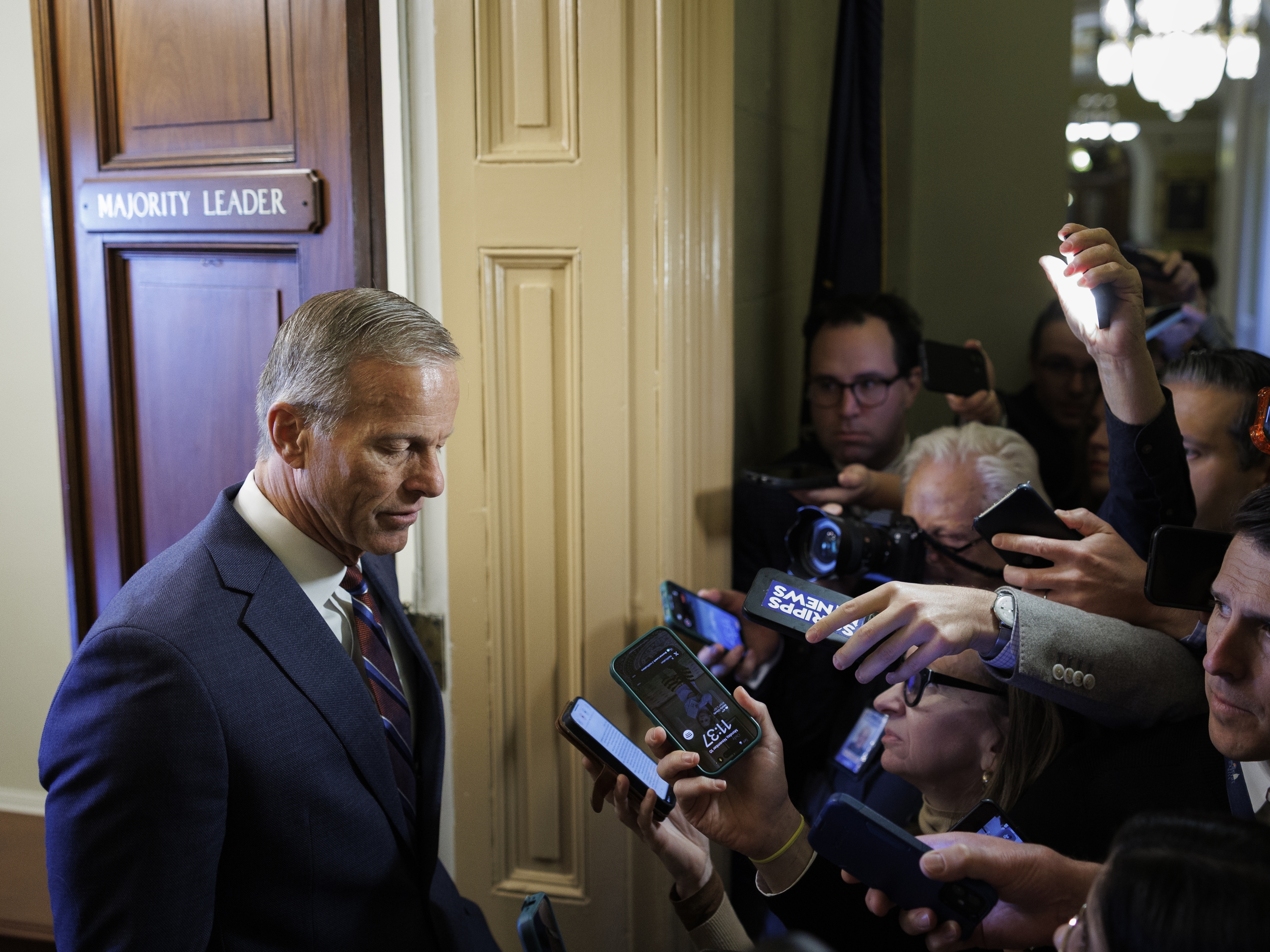 caption: Senate Majority Leader John Thune, R-S.D., speaks to reporters while walking to his office on November 10, 2025 on Capitol Hill.