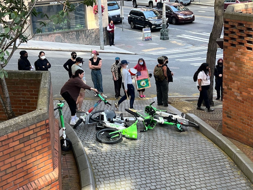 caption: Protesters drop Lime bikes and scooters onto a vehicle ramp at the Henry M. Jackson Federal Building in Seattle on June 10, 2025, hoping to block vehicles from leaving immigration court with detained immigrants.