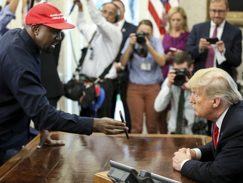 caption: Rapper Kanye West shows a picture of a plane on a phone to President Trump during a meeting in the Oval Office on Thursday.